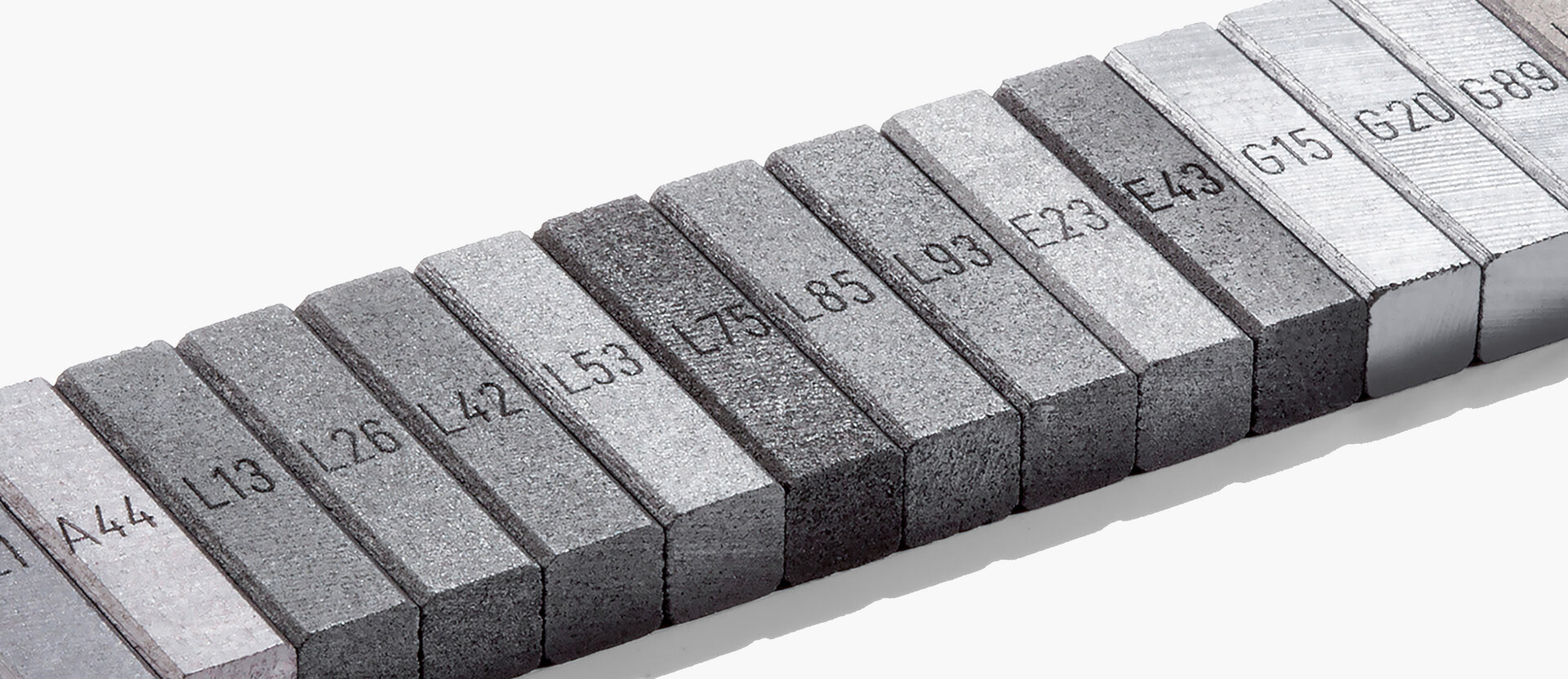  Reihe beschrifteter Graphitproben mit verschiedenen Werkstoffnummern – symbolisch für die Vielfalt industrieller Kohlenstoffmaterialien bei Schunk.
